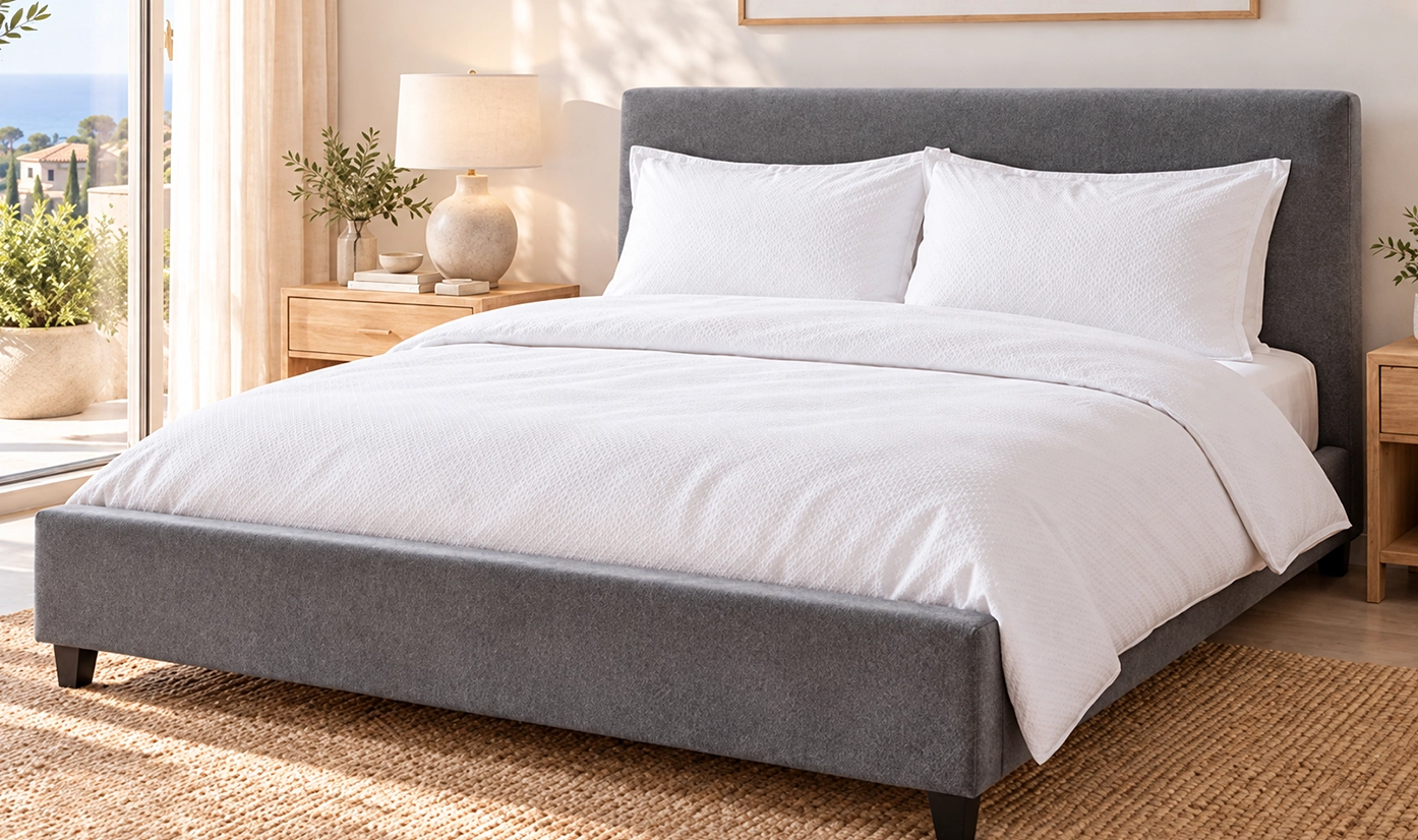 Gray upholstered bed with white bedding in a sunlit bedroom